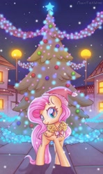 Size: 1600x2702 | Tagged: safe, artist:musicfirewind, fluttershy, pegasus, pony, christmas, christmas tree, christmas wreath, cute, female, folded wings, hat, head turn, holiday, looking at you, mare, night, outdoors, santa hat, shyabetes, smiling, solo, standing, tree, wings, wreath