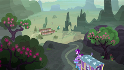 Size: 1440x810 | Tagged: safe, derpibooru import, screencap, starlight glimmer, trixie, pony, unicorn, to where and back again, desert, duo, female, flower, hat, mare, our town, scenery, tree, trixie's wagon, village, wizard hat