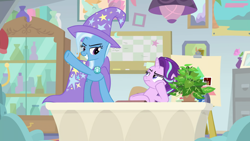 Size: 1920x1080 | Tagged: safe, derpibooru import, screencap, phyllis, starlight glimmer, trixie, pony, unicorn, a horse shoe-in, cape, clothes, duo, female, hat, mare, potted plant, raised hoof, table, trixie's cape, trixie's hat