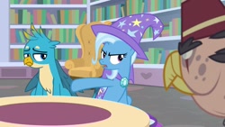 Size: 1920x1080 | Tagged: safe, derpibooru import, screencap, gallus, grampa gruff, trixie, griffon, pony, unicorn, a horse shoe-in, bookshelf, cape, clothes, female, hat, male, mare, quadrupedal, sofa, trixie's cape, trixie's hat