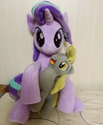 Size: 944x1154 | Tagged: safe, artist:nekokevin, derpy hooves, starlight glimmer, pegasus, pony, unicorn, series:nekokevin's glimmy, bed, duo, female, holding, holding a pony, irl, looking at you, mare, open mouth, photo, plushie, size difference, smiling