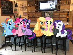 Size: 4032x3024 | Tagged: safe, derpibooru import, applejack, fluttershy, pinkie pie, rainbow dash, rarity, twilight sparkle, alicorn, earth pony, pegasus, pony, unicorn, bar, clock, espn, female, grin, head tilt, irl, lake house pub, mane six, mare, michigan, new buffalo, open mouth, photo, photoshop, ponies in real life, sitting, smiling, spread wings, stool, television, wings