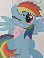 Size: 3024x4032 | Tagged: safe, derpibooru import, screencap, rainbow dash, pegasus, pony, bow, bunny ears, cropped, cute, dashabetes, female, looking at you, magazine, mare, merchandise, one eye closed, rainbow dash always dresses in style, sitting, smiling, wink