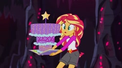 Size: 1100x618 | Tagged: safe, screencap, sunset shimmer, equestria girls, legend of everfree, book, cake, camp everfree outfits, clothes, crystal gala, food, legend you were meant to be, shorts, solo