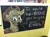 Size: 1118x835 | Tagged: safe, applejack, earth pony, pony, chalkboard, dialogue, looking at you, looking back, open mouth, photo, pun, sign, solo, text