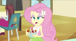 Size: 799x436 | Tagged: safe, screencap, fluttershy, velvet sky, equestria girls, apple, background human, bowl, cherry, cross-eyed, eyeshadow, food, frown, fruit salad, grapes, hair ornament, lidded eyes, makeup, open mouth, orange, salad, solo focus