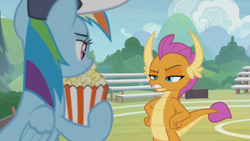 Size: 1366x768 | Tagged: safe, derpibooru import, screencap, rainbow dash, smolder, dragon, pegasus, pony, 2 4 6 greaaat, bleachers, coaching cap, displeased, dragoness, fangs, female, fence, field, flag, folded wings, food, glare, hands on hip, hat, horns, looking at each other, mare, multicolored mane, narrowed eyes, popcorn, raised eyebrow, smolder is not amused, teacher and student, teenaged dragon, teenager, unamused