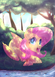 Size: 900x1260 | Tagged: safe, artist:drawntildawn, fluttershy, pegasus, pony, bush, cute, dappled sunlight, forest, looking at you, open mouth, prone, river, shade, shyabetes, smiling, solo, watermark