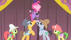 Size: 1280x720 | Tagged: safe, screencap, apple fritter, caramel, lucky clover, peachy sweet, pinkie pie, earth pony, pony, over a barrel, apple family member, clothes, costume, eyes closed, lifting, saloon pinkie, singing, stage, you gotta share