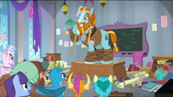 Size: 1574x888 | Tagged: safe, derpibooru import, screencap, gallus, rockhoof, sandbar, silverstream, smolder, yona, earth pony, pony, a rockhoof and a hard place, beard, braid, classroom, desk, facial hair, male, moustache, rockhoof's shovel, shovel, stallion