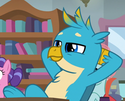 Size: 678x550 | Tagged: safe, derpibooru import, screencap, gallus, griffon, pony, a rockhoof and a hard place, arm behind back, arm behind head, background pony, bookshelf, chest fluff, cropped, cute, gallabetes, inkwell, male, offscreen character, paws, smiling, smirk, solo, wings