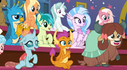 Size: 1619x893 | Tagged: safe, derpibooru import, screencap, amber grain, clever musings, fuchsia frost, gallus, malachite (sailor moon), ocellus, sandbar, silverstream, smolder, snowy quartz, yona, changedling, changeling, dragon, earth pony, griffon, hippogriff, pony, unicorn, yak, a rockhoof and a hard place, background pony, cheering, clapping, dragoness, female, friendship student, male, mare, raised hoof, stallion, student six