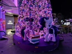 Size: 960x720 | Tagged: safe, derpibooru import, photographer:hongkoon, rarity, twilight sparkle, twilight sparkle (alicorn), alicorn, pony, unicorn, book, christmas, christmas tree, holiday, night, purple, singapore, statue, tree