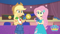 Size: 1057x594 | Tagged: safe, screencap, applejack, fluttershy, best in show: the victory lap, better together, equestria girls, looking at you, microphone, smiling