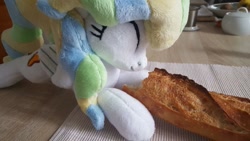 Size: 1207x679 | Tagged: safe, artist:ketika, vapor trail, pegasus, pony, baguette, bread, cute, eating, eyes closed, food, happy, irl, kitchen, lying down, photo, plushie, solo, table, vaporbetes