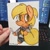 Size: 1080x1080 | Tagged: safe, artist:mintmouse0_o, derpibooru import, applejack, anthro, earth pony, unguligrade anthro, chibi, clothes, computer, discord (program), female, freckles, geralt of rivia, irl, missing accessory, photo, sack, slit eyes, smiling, sword, traditional art, weapon