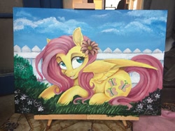 Size: 900x675 | Tagged: safe, artist:dvixie, derpibooru import, twibooru import, fluttershy, pegasus, pony, canvas, cute, deleted from derpibooru, female, fence, flower, flower in hair, grass, lying down, mare, open mouth, painting, prone, shyabetes, signature, solo, traditional art