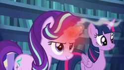 Size: 1000x562 | Tagged: safe, derpibooru import, screencap, starlight glimmer, twilight sparkle, twilight sparkle (alicorn), alicorn, pony, unicorn, every little thing she does, duo, duo female, female, glowing horn, happy, horn, indoors, library, looking ahead, looking forward, looking up, magic, magic aura, overheated horn, smiling, smoke, twilight's castle