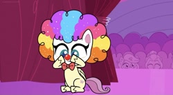 Size: 828x457 | Tagged: safe, derpibooru import, screencap, fluttershy, pegasus, pony, lolly-pop, my little pony: pony life, spoiler:pony life s02e19, backstage, bowtie, clown, clown makeup, clown nose, clown wig, crowd, curtains, cute, female, flutterclown, logo, shyabetes, sitting, solo