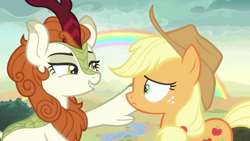 Size: 1920x1080 | Tagged: safe, derpibooru import, screencap, applejack, autumn blaze, earth pony, kirin, pony, season 8, sounds of silence, applejack's hat, clothes, cowboy hat, duo, duo female, female, frown, grin, hat, lidded eyes, lip bite, looking at each other, mare, rainbow, smiling
