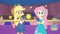 Size: 3410x1920 | Tagged: safe, derpibooru import, screencap, applejack, fluttershy, best in show: the victory lap, better together, equestria girls, applejack's hat, belt, best in show logo, clothes, cowboy hat, cutie mark, cutie mark on clothes, denim skirt, female, geode of fauna, geode of super strength, hairpin, hand on hip, hat, jewelry, magical geodes, microphone, necklace, skirt, smiling