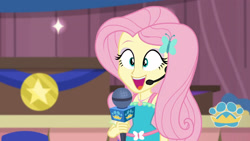 Size: 3410x1920 | Tagged: safe, derpibooru import, screencap, fluttershy, best in show: the victory lap, better together, equestria girls, best in show logo, cute, female, geode of fauna, hairpin, jewelry, magical geodes, microphone, necklace, open mouth, shyabetes, smiling, solo