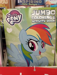 Size: 3120x4160 | Tagged: safe, derpibooru import, rainbow dash, pegasus, pony, coloring book, dollar tree, female, high res, irl, irl photo, mare, my little pony jumbo coloring book, my little pony logo, open mouth, open smile, photo, raised hoof, raised leg, smiling, solo, spread wings, wings