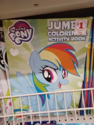 Size: 3000x4000 | Tagged: safe, derpibooru import, rainbow dash, pegasus, pony, coloring book, dollar tree, family dollar, female, high res, irl, mare, my little pony jumbo coloring book, my little pony logo, open mouth, open smile, photo, price tag, raised hoof, raised leg, smiling, solo, spread wings, sticker, wings