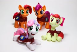 Size: 4096x2731 | Tagged: safe, artist:dustysculptures, derpibooru import, apple bloom, babs seed, scootaloo, sweetie belle, earth pony, pegasus, pony, unicorn, bow, cape, clothes, cmc cape, craft, cutie mark crusaders, female, filly, foal, hair bow, photo, sculpture, smiling, traditional art