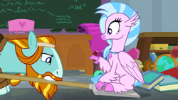 Size: 1920x1080 | Tagged: safe, derpibooru import, screencap, rockhoof, silverstream, classical hippogriff, earth pony, hippogriff, pony, a rockhoof and a hard place, season 8, spoiler:s08, chalkboard, classroom, colored hooves, desk, duo, female, jewelry, male, mare, necklace, rockhoof's shovel, shovel, sittin on shovel, sitting, stallion