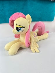 Size: 780x1040 | Tagged: safe, artist:kazzysplush, derpibooru import, fluttershy, pegasus, pony, eyelashes, female, for sale, irl, lidded eyes, lying down, mare, narrowed eyes, photo, plushie, prone, sitting, smiling, solo, sploot