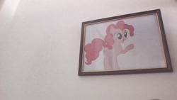 Size: 1280x720 | Tagged: safe, derpibooru import, pinkie pie, earth pony, female, hooves, irl, mare, open mouth, paper, photo, picture, picture frame, pointing, smiling, solo, standing, wall