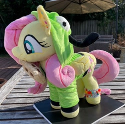 Size: 2048x2036 | Tagged: safe, artist:orky, derpibooru import, fluttershy, pegasus, pony, clothes, ear piercing, earring, female, folded wings, food, happy, hood up, hoodie, invader zim, irl, jewelry, mare, photo, piercing, plushie, solo, standing, waffle, wings