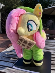 Size: 1536x2048 | Tagged: safe, artist:orky, derpibooru import, fluttershy, pegasus, pony, clothes, ear piercing, earring, female, folded wings, food, happy, hood up, hoodie, invader zim, irl, jewelry, mare, photo, piercing, plushie, solo, standing, waffle, wings