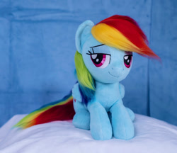 Size: 1098x948 | Tagged: safe, artist:buttercupbabyppg, derpibooru import, rainbow dash, pegasus, pony, female, folded wings, irl, lying down, mare, photo, plushie, prone, smiling, solo, wings