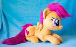 Size: 1914x1195 | Tagged: safe, artist:buttercupbabyppg, derpibooru import, scootaloo, pegasus, pony, female, filly, foal, happy, irl, lying down, photo, plushie, prone, smiling, solo, spread wings, wings