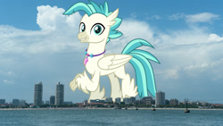 Size: 1920x1080 | Tagged: safe, artist:jhayarr23, derpibooru import, edit, editor:jaredking779, terramar, classical hippogriff, hippogriff, beach, highrise ponies, irl, jewelry, looking at you, macro, male, necklace, photo, ponies in real life, raised claw, smiling, solo, story included