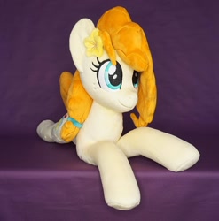 Size: 1296x1312 | Tagged: safe, artist:egalgay, derpibooru import, pear butter, earth pony, pony, female, flower, flower in hair, happy, irl, lying down, mare, photo, plushie, prone, smiling, solo, sploot