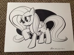 Size: 1024x768 | Tagged: safe, artist:thom zahler, derpibooru import, fluttershy, pegasus, pony, g4, 2014, black and white, commission, female, folded wings, grayscale, heroescon, heroescon 2014, mare, monochrome, photo, raised hoof, raised leg, smiling, solo, tail, traditional art, wings