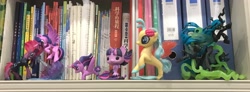 Size: 3544x1307 | Tagged: safe, derpibooru import, photographer:jess181307, princess skystar, queen chrysalis, tempest shadow, twilight sparkle, twilight sparkle (alicorn), alicorn, changeling, changeling queen, g4, book, bookshelf, chinese, funko, funko pop!, irl, photo, toy