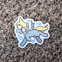 Size: 971x971 | Tagged: safe, artist:punkittdev, derpibooru import, derpy hooves, pegasus, pony, g4, blonde, blonde mane, blonde tail, bubble, carpet, colored, derp, eye clipping through hair, eyelashes, female, flat colors, gray coat, irl, mare, no catchlights, no pupils, open mouth, open smile, photo, raised hoof, raised leg, running, small wings, smiling, solo, spread wings, sticker, sticker design, tail, wings